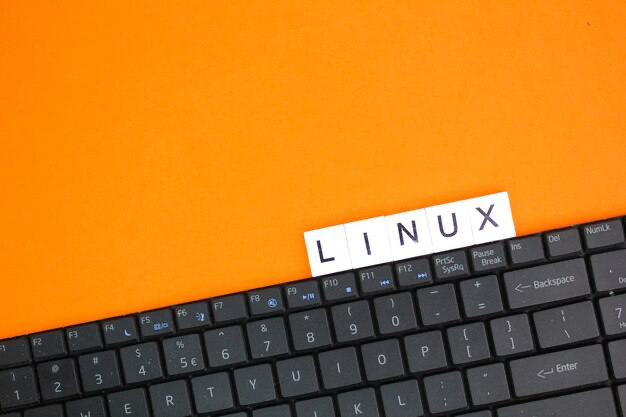 The word Linux on cubes next to the keyboard on an orange background