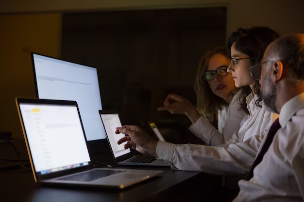 Three people sitting and working in front of a computer